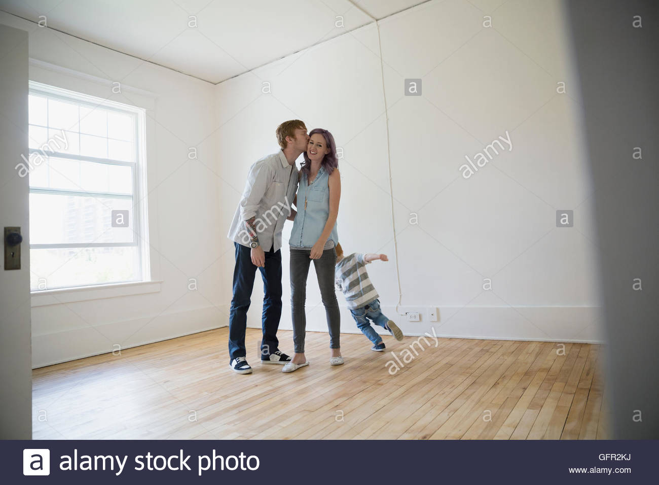 Junge Familie in leeren neuen Haus küssen Stockfoto