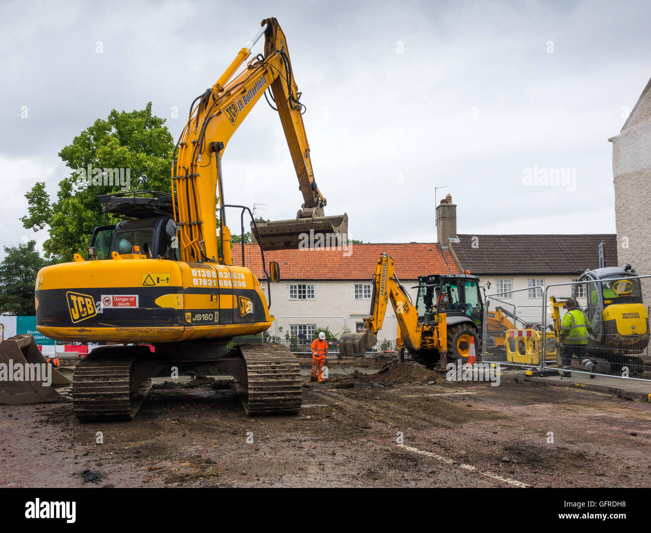 Arbeiter mit einem JCB Bagger und ein JS160 verfolgt Lader Re-Verlegung einer Straße in einer Stadt-Zentrum-Website Stockfoto