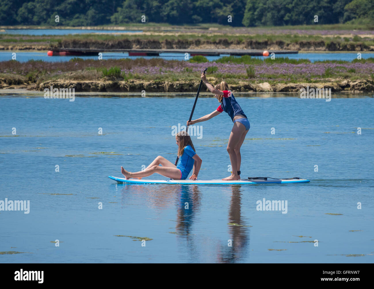 Zwei Mädchen genießen aufstehen Paddle boarding in Newtown Fluß auf der Isle Of Wight, UK Stockfoto