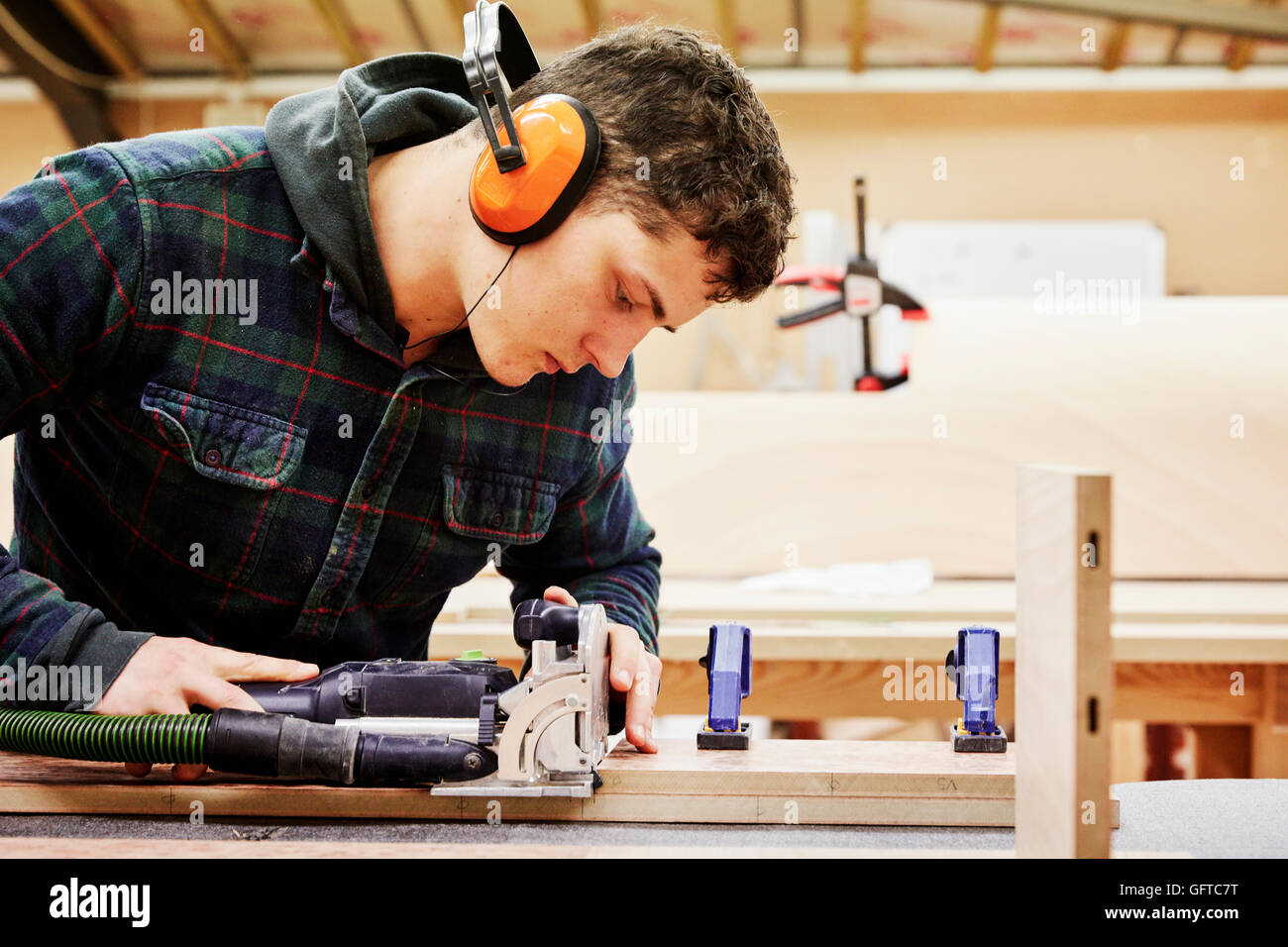 Ein Möbel Workshop A junger Mann mit Tools, um ein Stück Holz zu gestalten Stockfoto