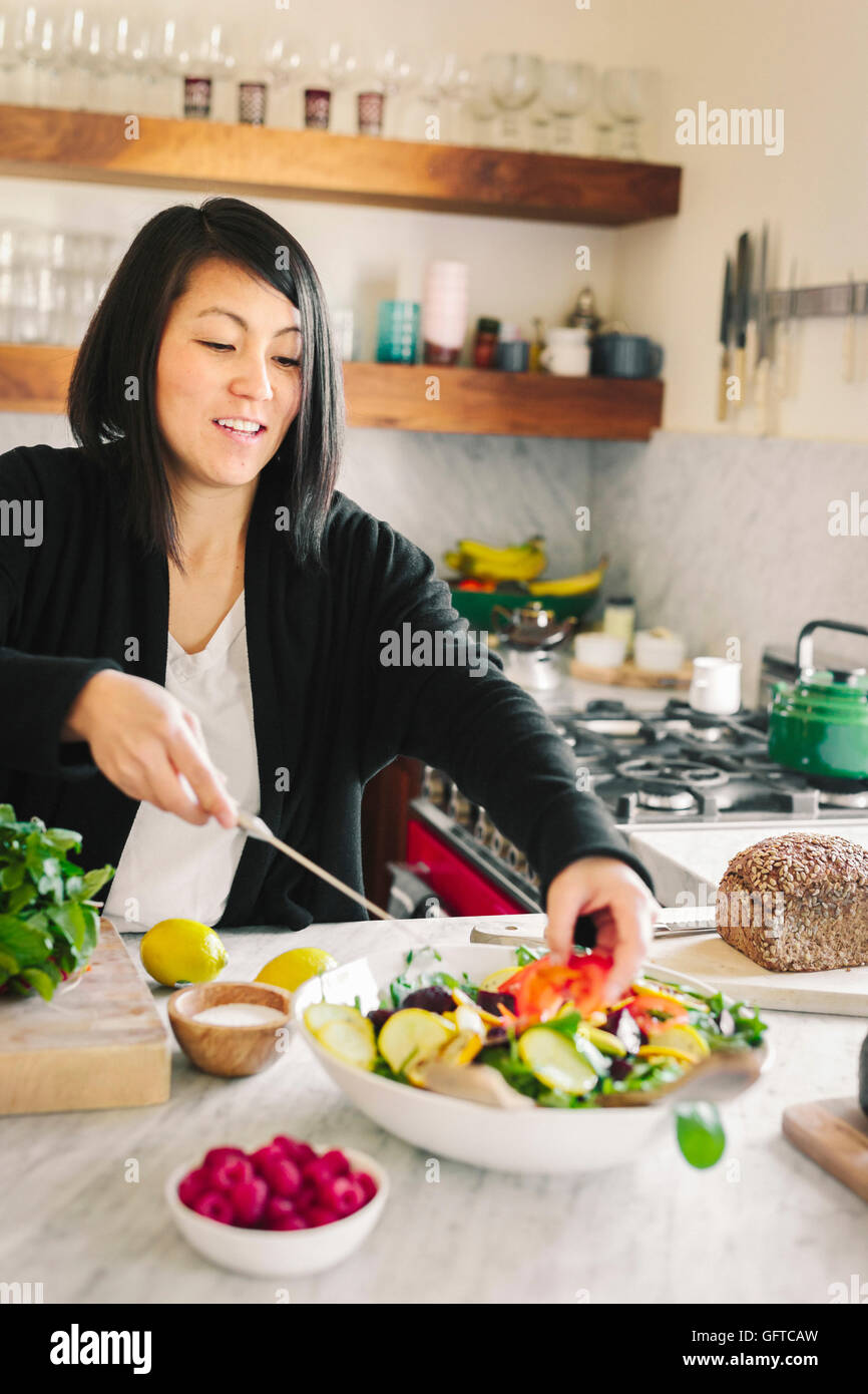 Eine Frau in einer Küche und bereitet einen Salat-Teller mit frischem Gemüse Stockfoto