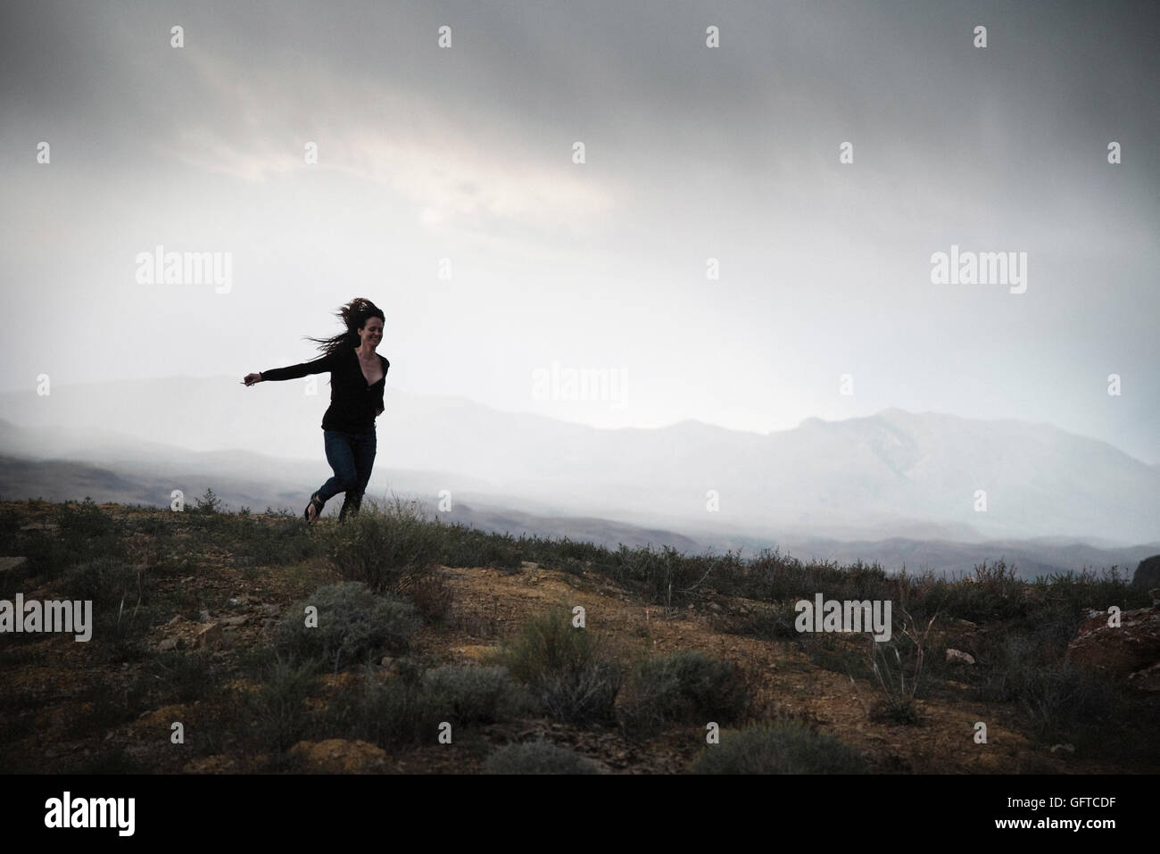 Frau läuft in einem Prärie bei bewölktem Himmel Stockfoto