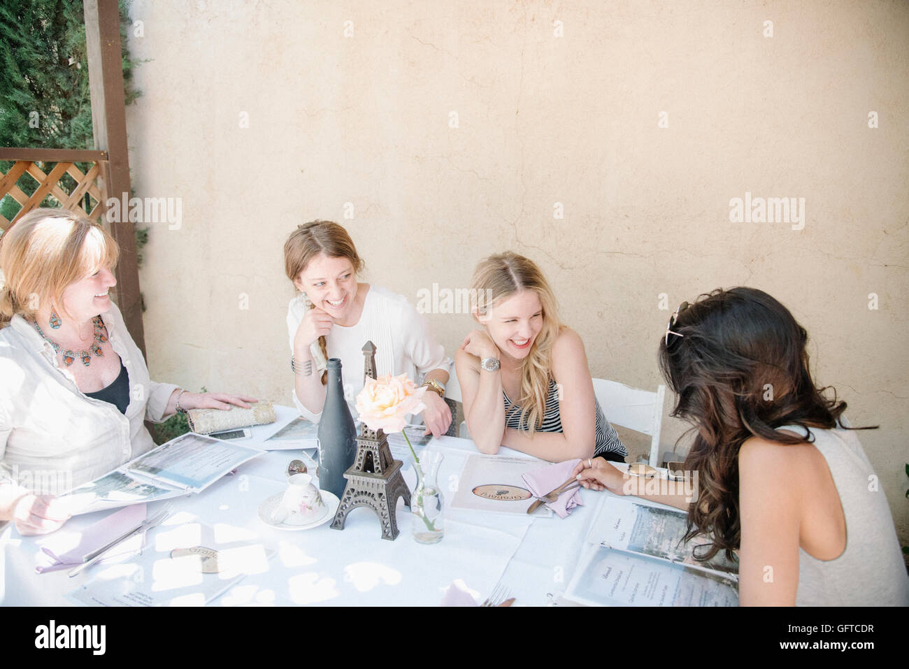 Vier Frauen sitzen an einem Tisch lächelnd und chatten Stockfoto