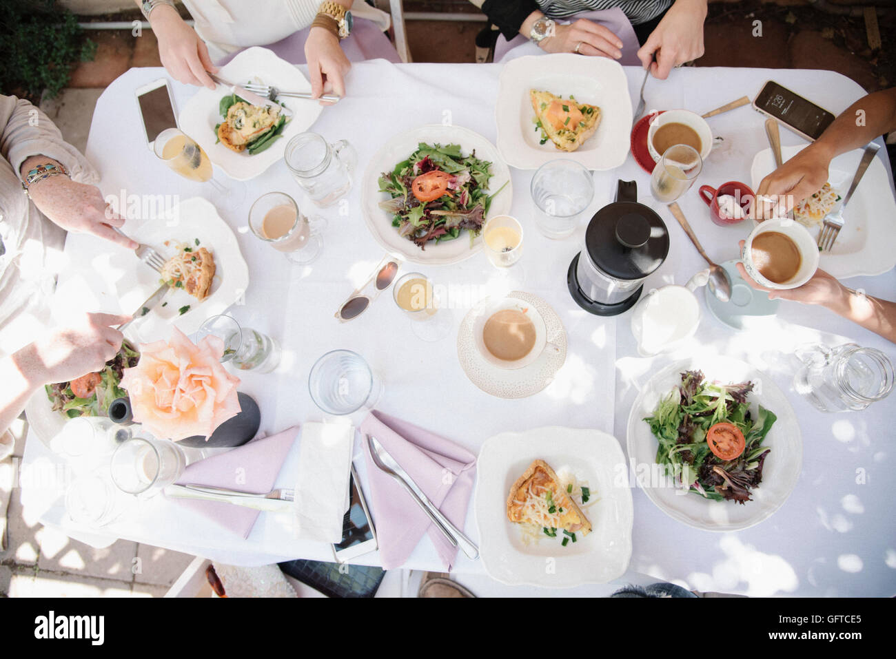 Erhöhte Ansicht von vier Frauen sitzen um einen Tisch mit Speisen und Getränken Platten mit Omelett und Salat Kaffee und Champagner Stockfoto