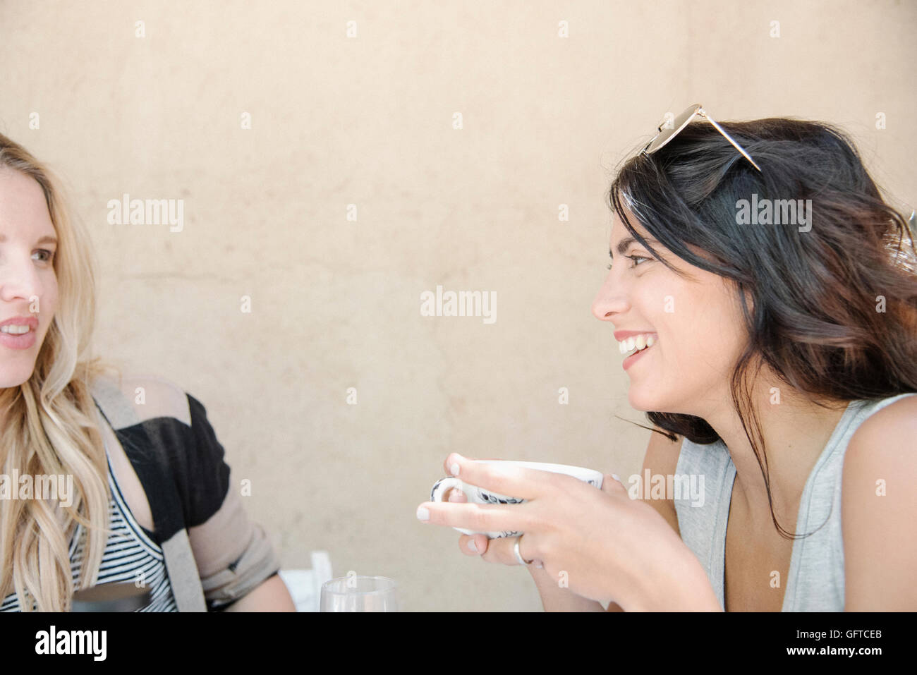 Porträt einer jungen Frau mit langen braunen Haaren hält eine Tasse im Chat an einen Freund Stockfoto