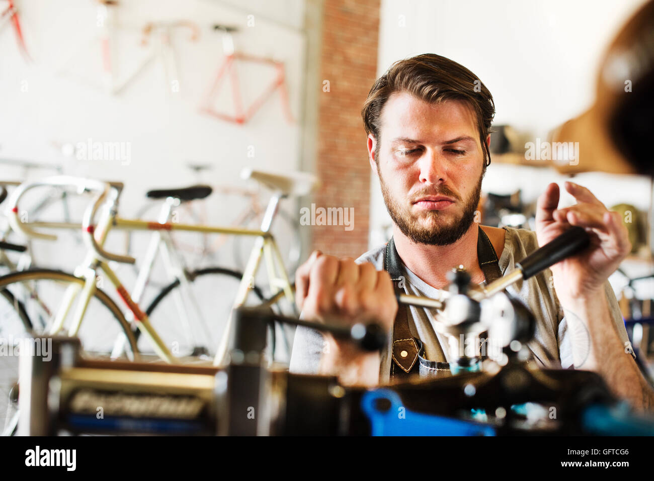Ein Mann, der arbeitet in einer Fahrradwerkstatt, die Überprüfung der Fahrradrahmen Stockfoto Ein Mann, der arbeitet in einer Fahrradwerkstatt, die Überprüfung der Fahrradrahmen Stockfoto