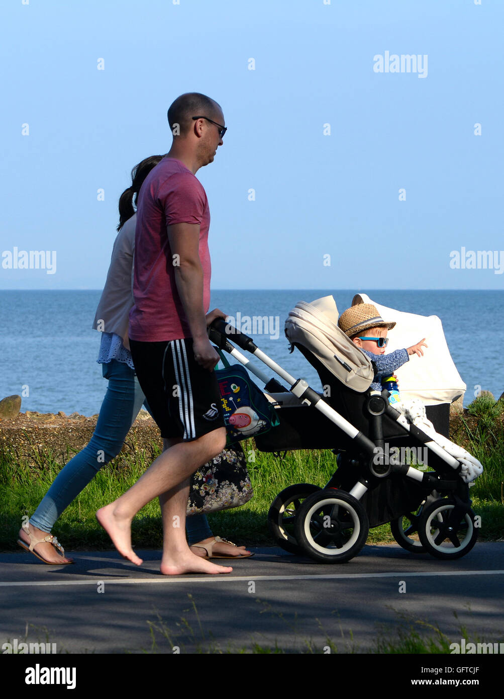 Baby junge Eltern von Kinderwagen am Strand Swansea Bay weist die Sehenswürdigkeiten