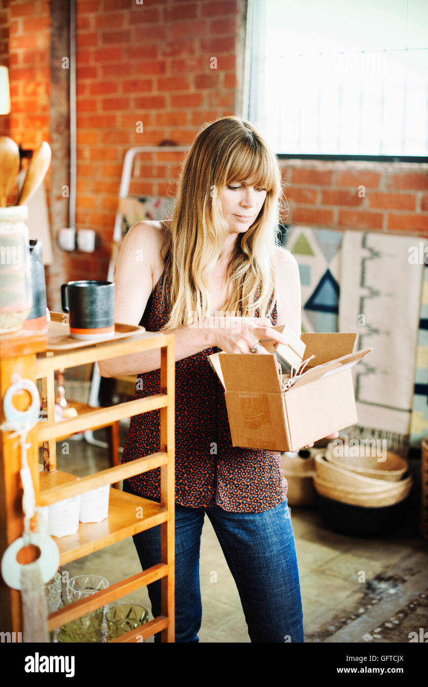 Frau in einem Geschäft hält eine kleine Pappschachtel mit Ware Stockfoto