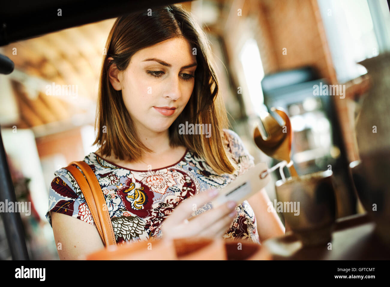 Junge Frau in einem Geschäft auf der Suche zu einem Preis Stockfoto