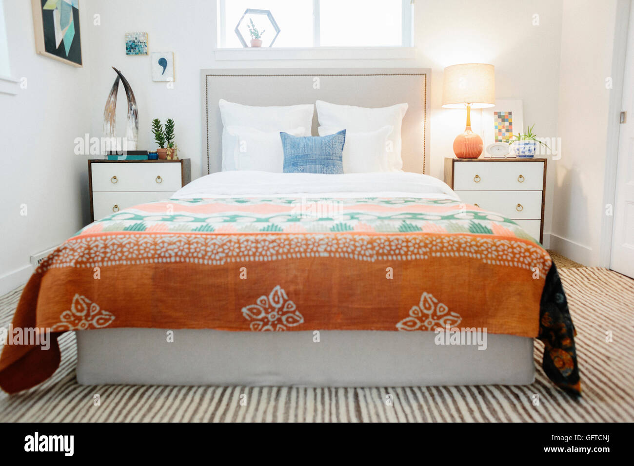 Ein Schlafzimmer in einem Apartment mit einem Doppelbett ausgestattet und neben Schränke und eine lebendige gemusterten Tagesdecke Stockfoto
