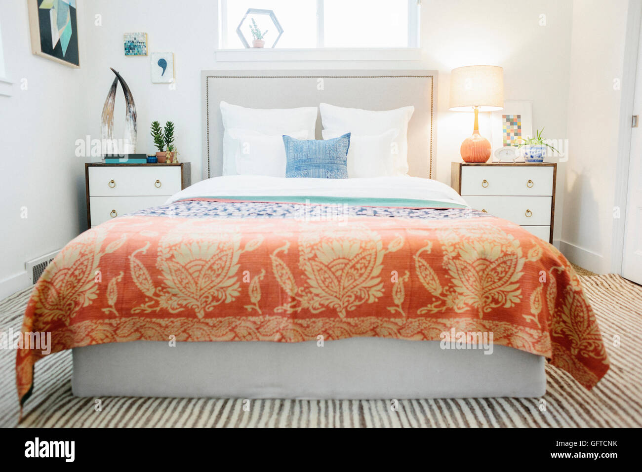 Ein Schlafzimmer in einem Apartment mit einem Doppelbett ausgestattet und neben Schränke und eine lebendige gemusterten Tagesdecke Stockfoto