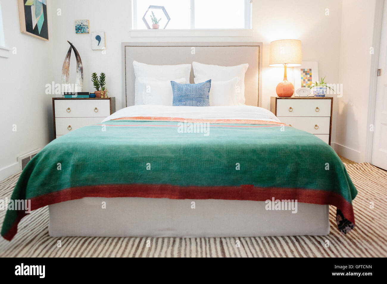 Ein grüner Stoff Quilt mit roten Trimm über ein Doppelbett in einem hellen luftigen Wohnung Stockfoto