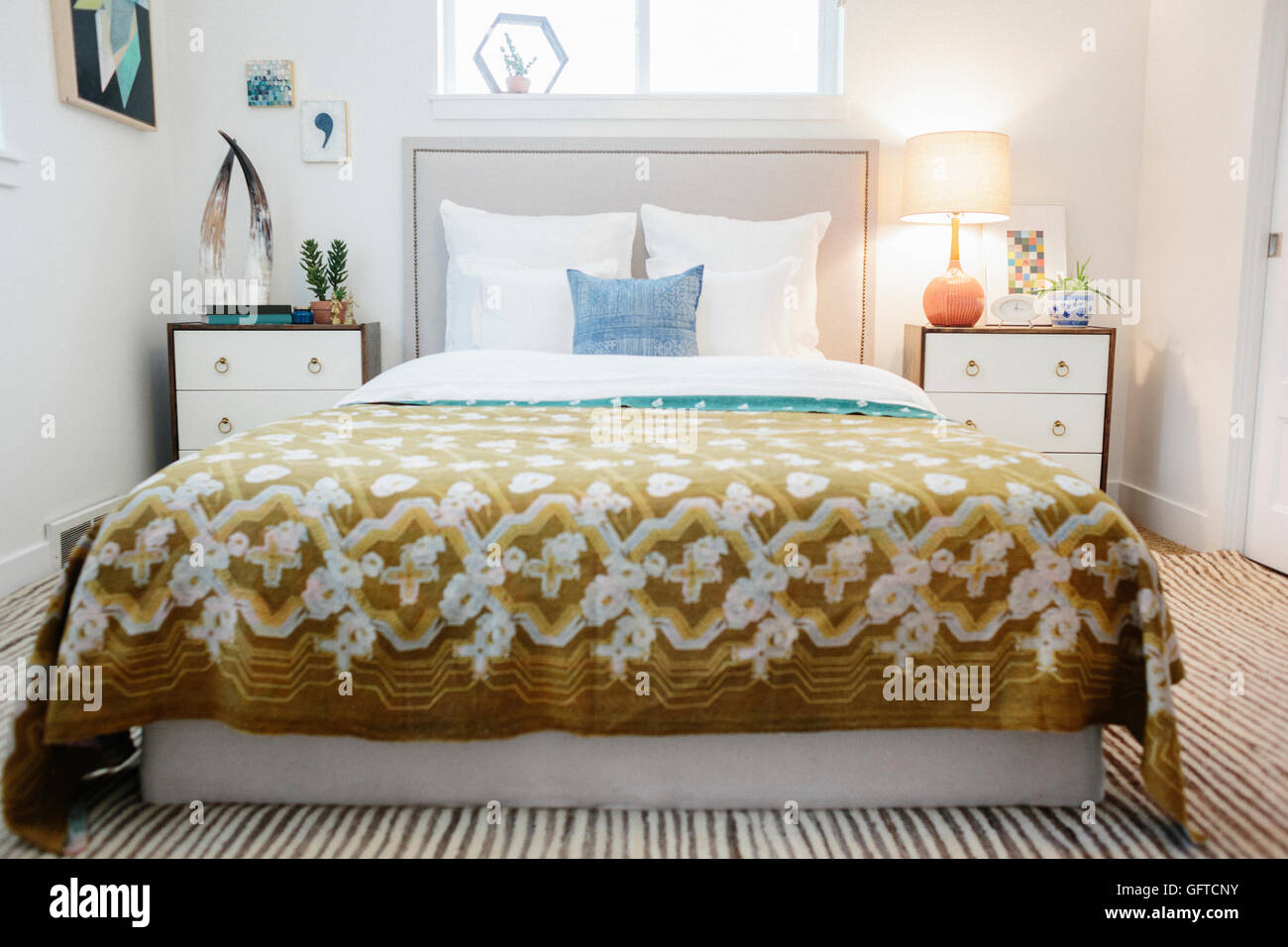Ein Schlafzimmer in einem Apartment mit einem Doppelbett mit einer gemusterten Retro-Look-Tagesdecke bedeckt Stockfoto