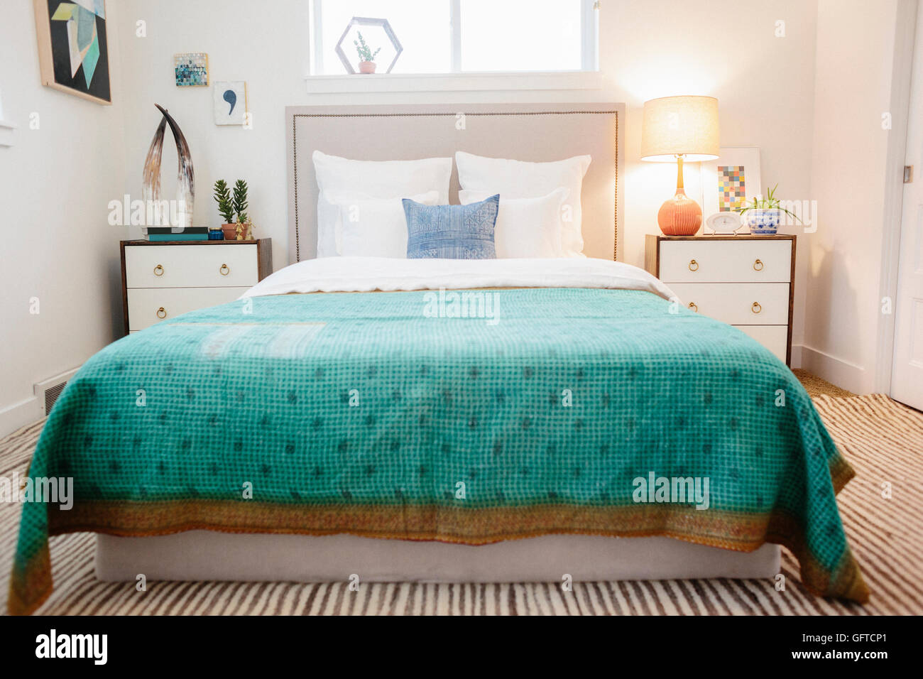 Ein Schlafzimmer in einem Apartment mit einem Doppelbett ausgestattet und neben Schränken und einem grünen überprüft gemusterten Bettdecke Stockfoto