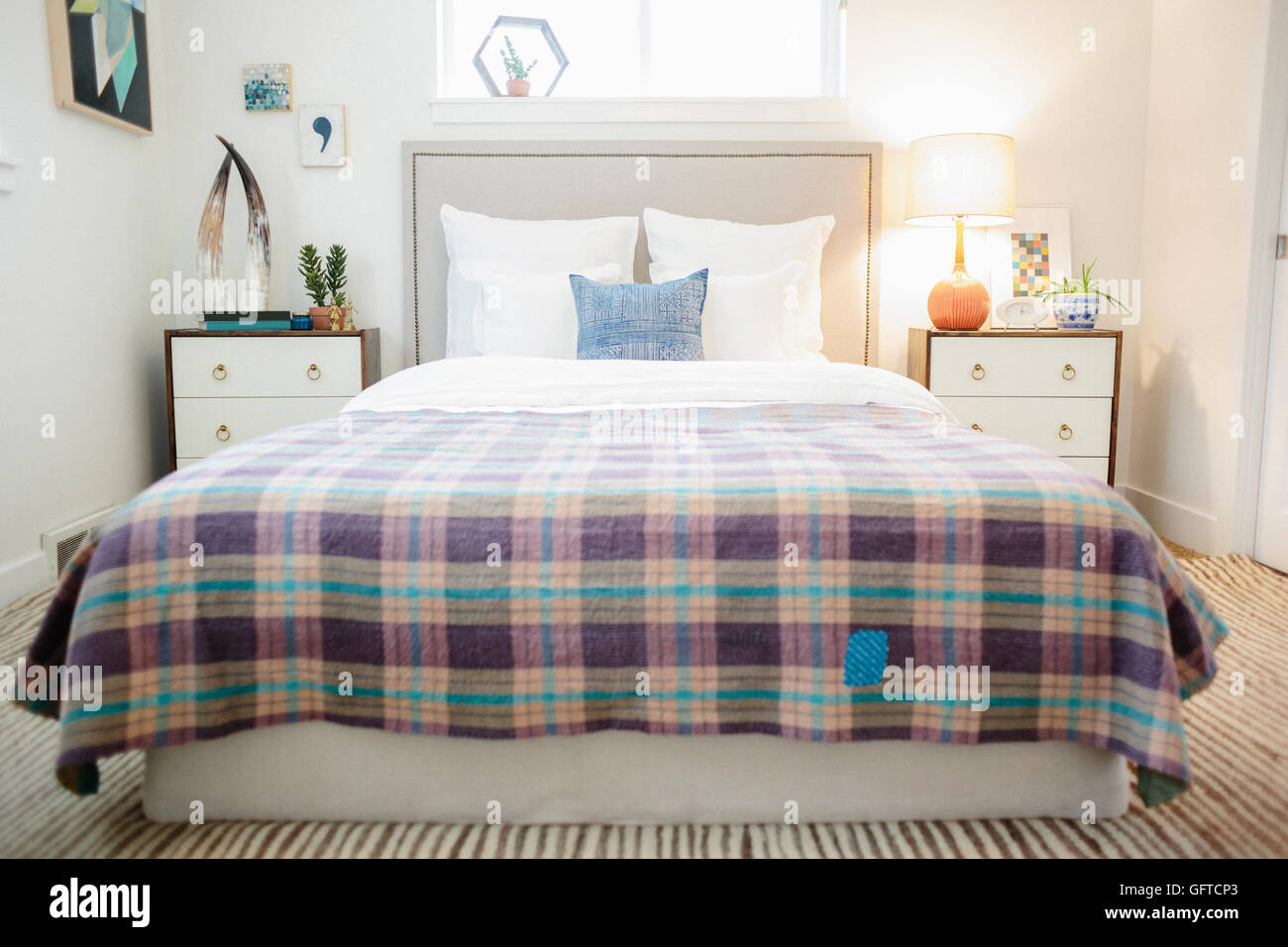 Ein Schlafzimmer in einem Doppelbett Wohnung mit einem aufgegebenen lila und Creme Bettdecke bedeckt Stockfoto