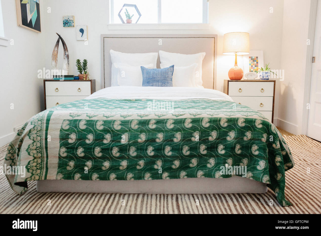 Ein Schlafzimmer in einem Apartment mit einem Doppelbett ausgestattet und neben Schränken und einem grünen Stoff gemustert Tagesdecke Stockfoto