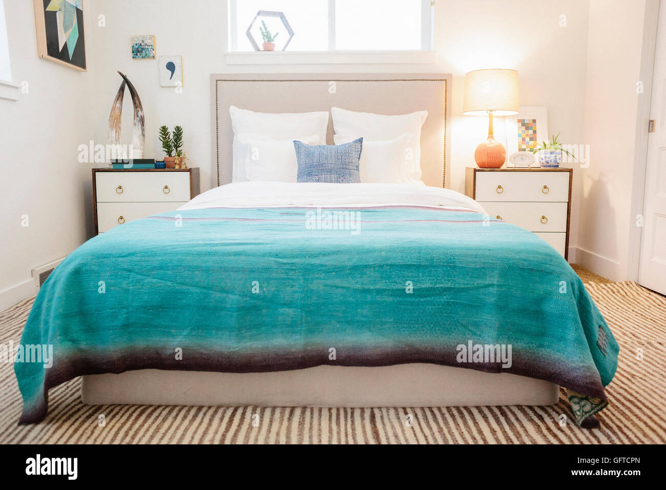 Ein Schlafzimmer in einem Apartment mit einem Doppelbett ausgestattet und neben Schränke und eine grüne Decke auf dem Bett Stockfoto