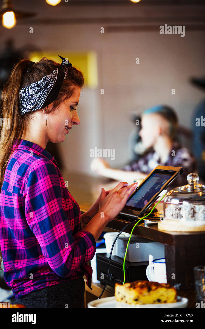 Eine Frau hinter der Theke über den Touchscreen auf der Kasse arbeiten Stockfoto