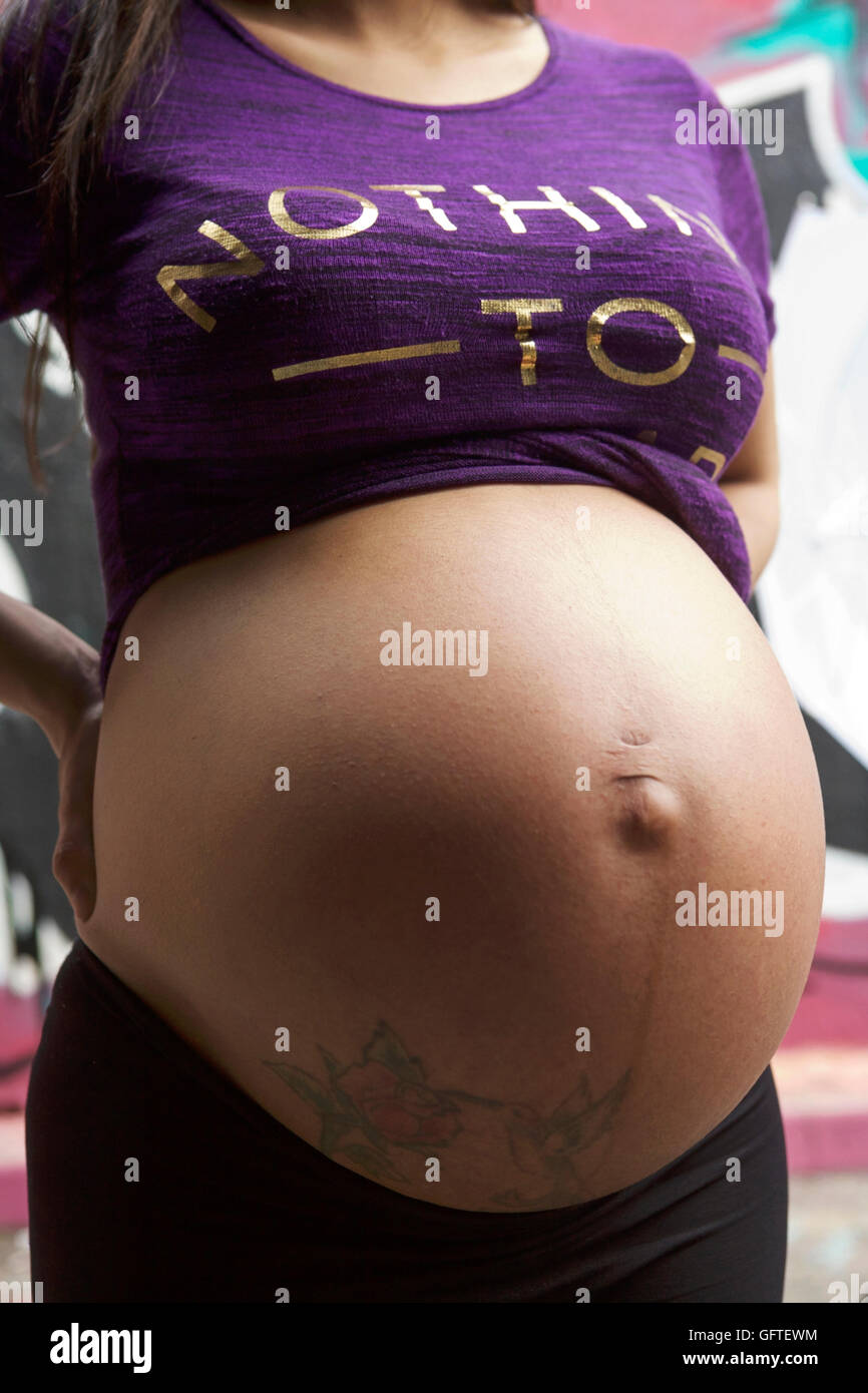 Bauch einer jungen Frau, die im 9. Monat schwanger ist und Dehnungsstreifen zeigt. Schwangerschaftsabbruch. Bauchnabel. Mutterleib-Transplantation. Schwangerschaftsbauch. Fruchtbarkeit des Impfstoffs. Stockfoto