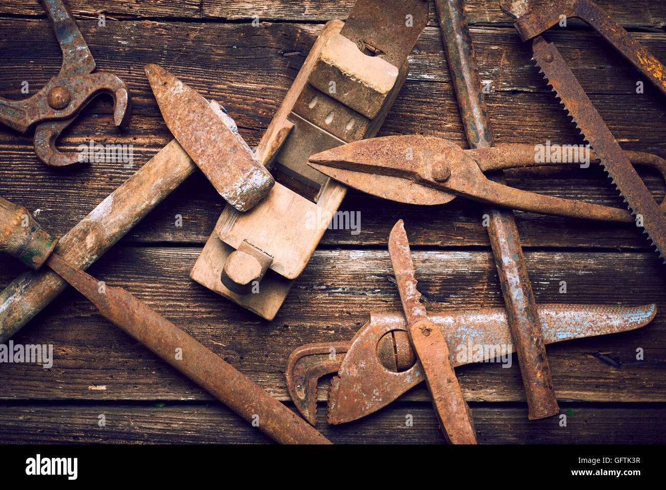 Grunge alte verrostete Werkzeuge auf einer hölzernen Hintergrundverarbeitung (Prozess-) Stockfoto