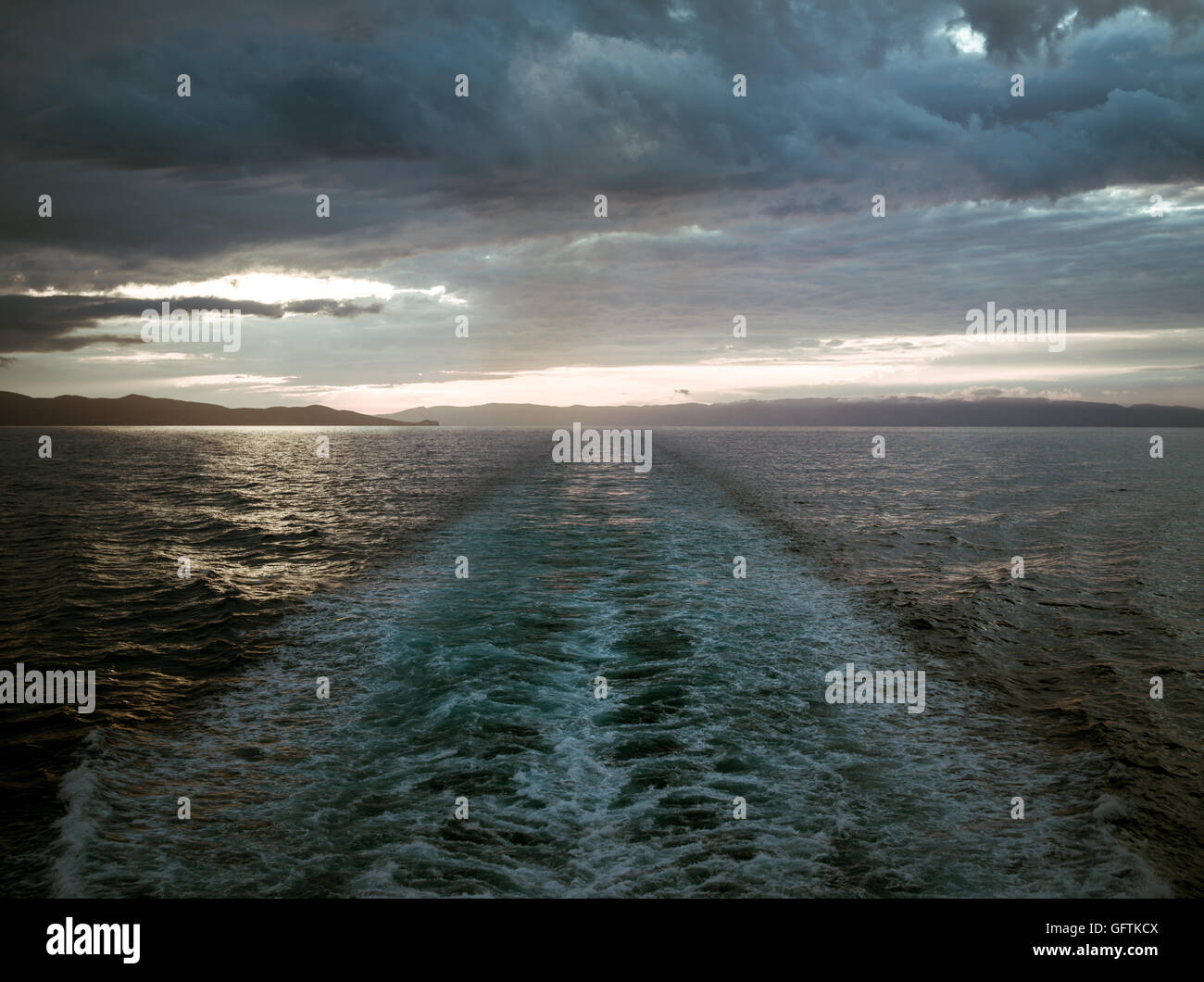 Sonnenuntergang im Meer und eine Spur aus dem Schiff in einem Sturm Stockfoto