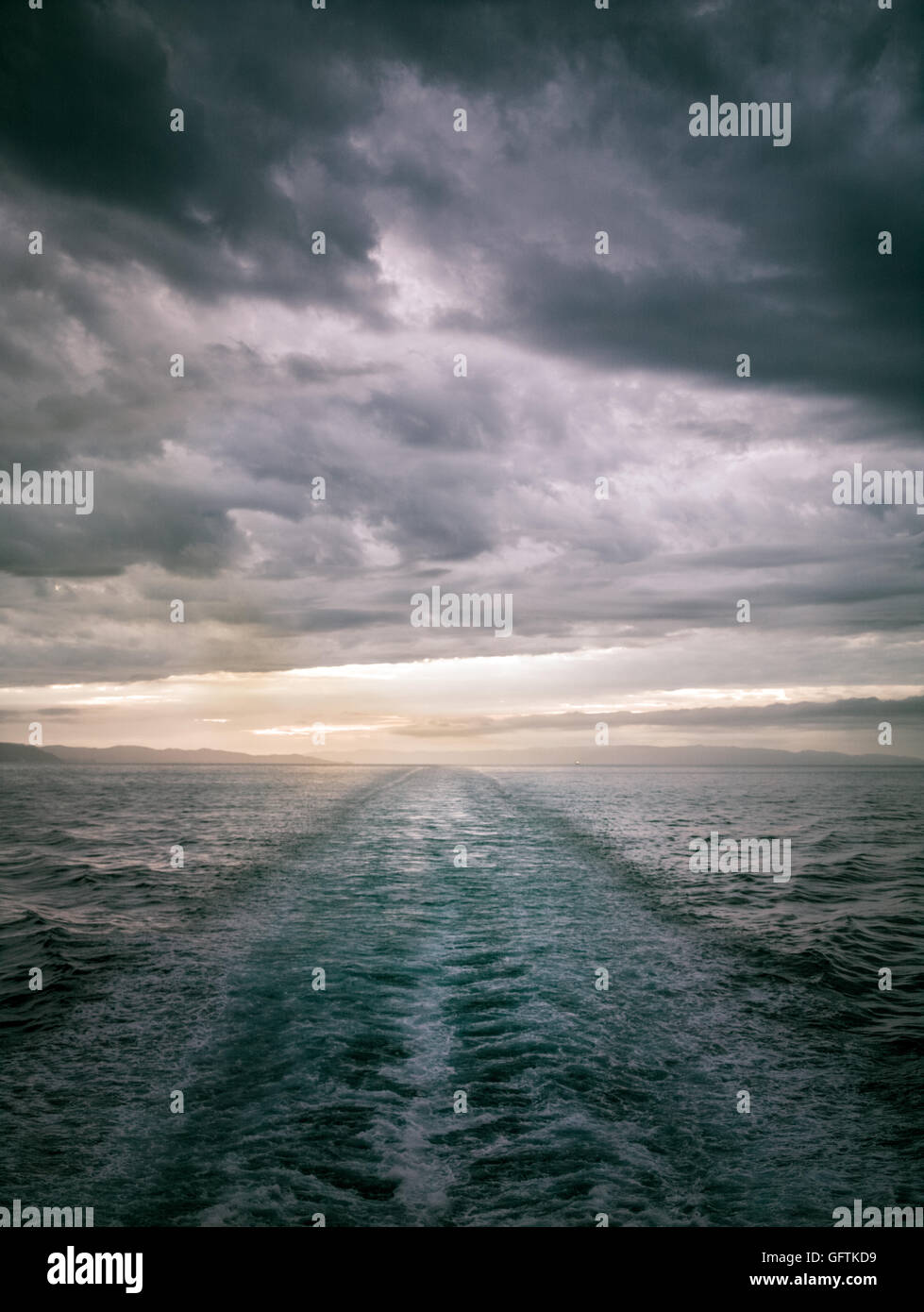 Sonnenuntergang im Meer und eine Spur aus dem Schiff in einem Sturm Stockfoto