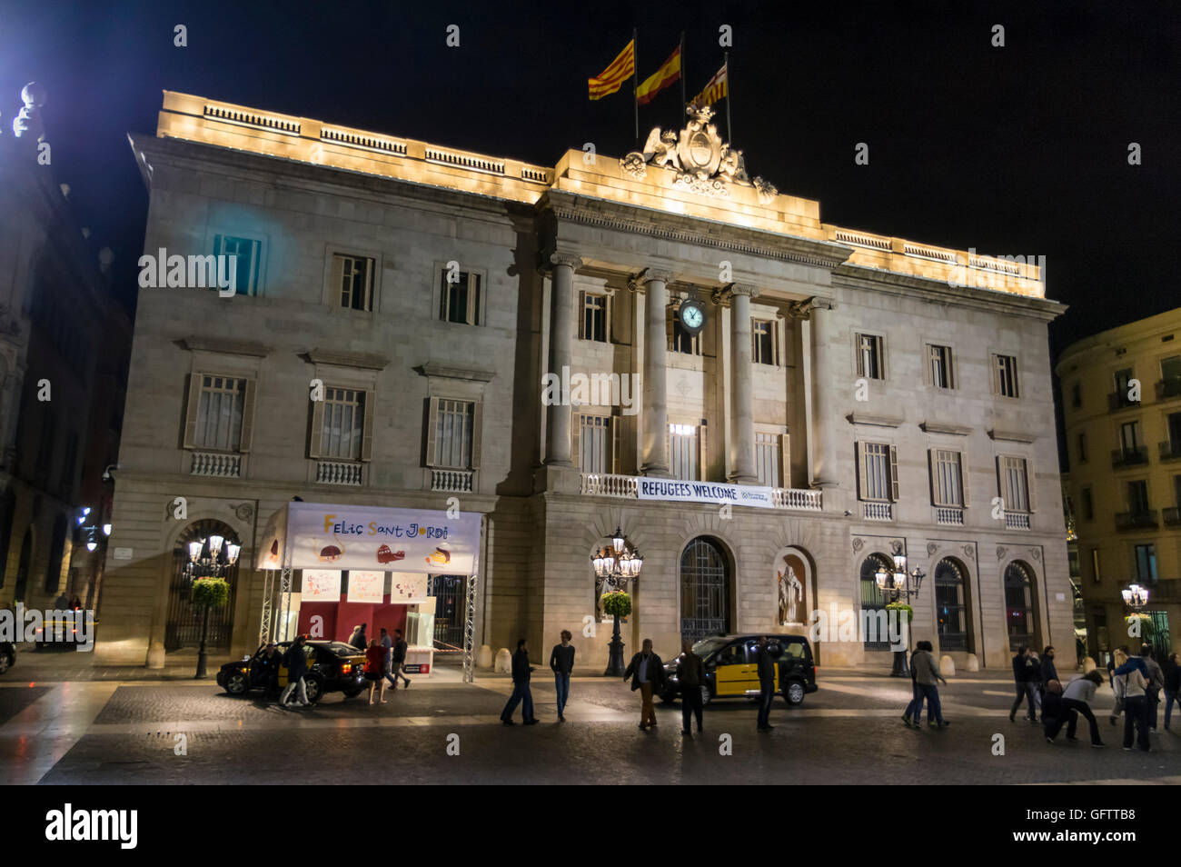 Fassade der Casa De La Ciutat, Rathaus von Barcelona, in der Nacht, mit einem Banner "Flüchtlinge aufzunehmen". Stockfoto