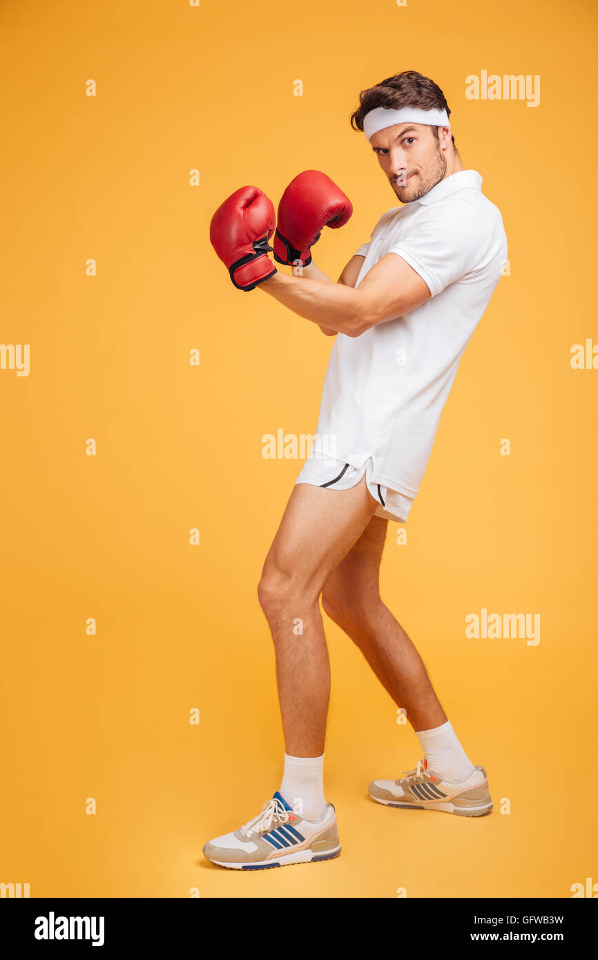 Starker junger Mann Boxer in rote Handschuhe stehen und posiert auf gelbem Hintergrund Stockfoto