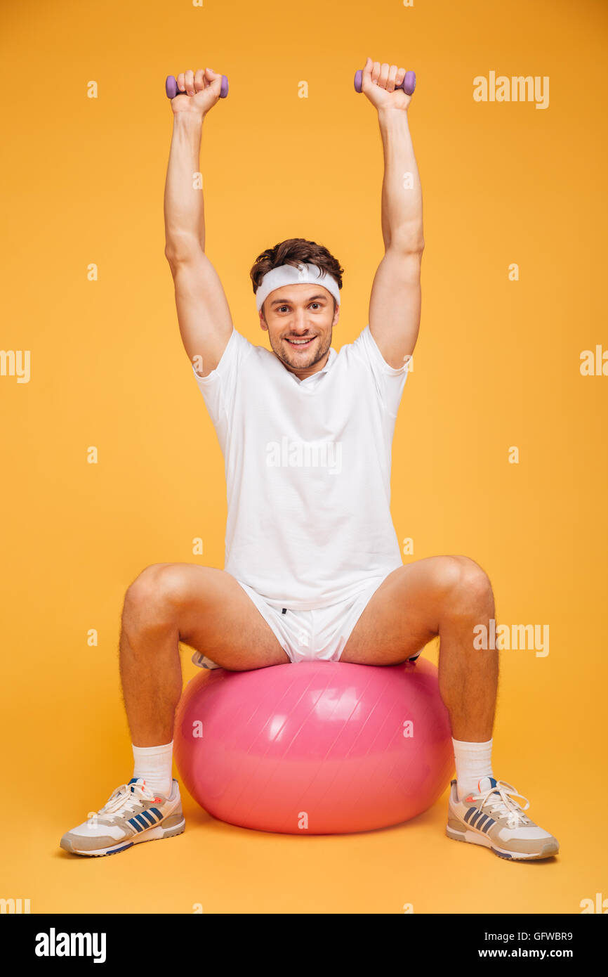 Portrat Eines Mannes Sport Sitzen Auf Der Fitness Ball Und Ubungen Mit Kleinen Hanteln Isoliert Auf Einem Orangefarbenen Hintergrund Stockfotografie Alamy