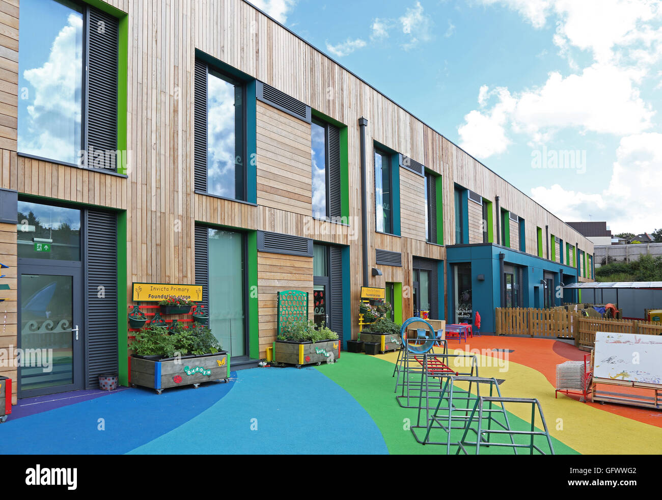 Exterieur der Invicta Grundschule in Südlondon. Eine neue Holz verkleideten Struktur mit Regenbogenfarben Spielplatz Oberfläche Stockfoto