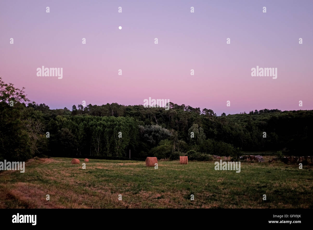 Mond kommt in der Dämmerung über Felder mit Heuballen Le Lot und Dordogne Regionen von Frankreich Juli 2016 Stockfoto