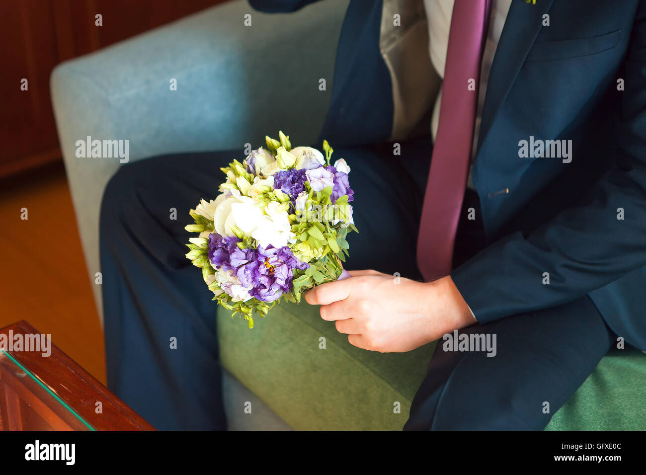 gut gekleideter Mann mit einem Blumenstrauß, weiße Rosen. Feiertage und Feste. Tag der Hochzeit. Stockfoto