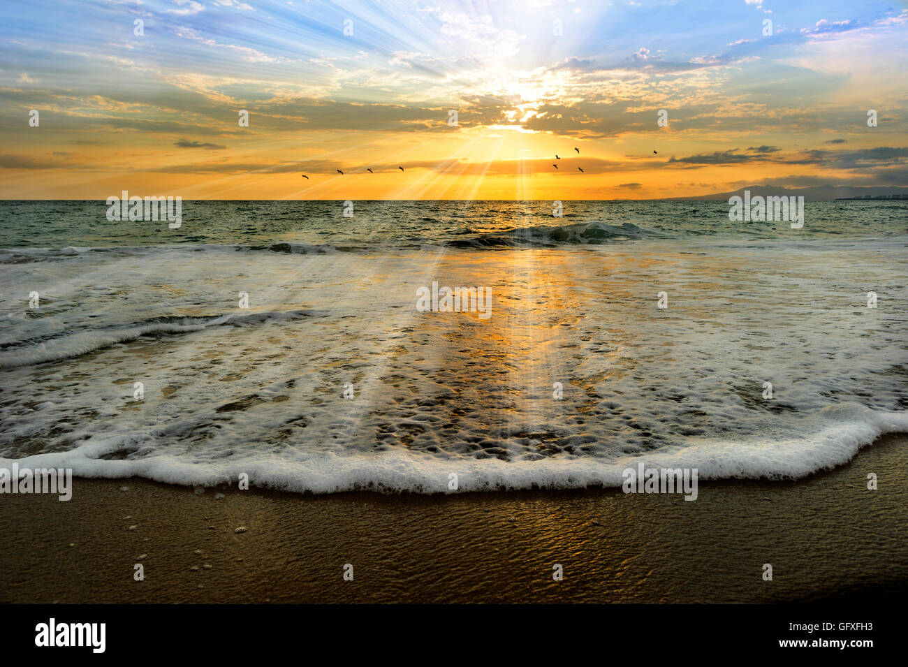 Meer Sonnenuntergang Strahlen ist eine ätherische Meer malerisch mit Sonnenstrahlen platzen her von der untergehenden Sonne wie eine sanfte Welle ans Ufer kommt Stockfoto