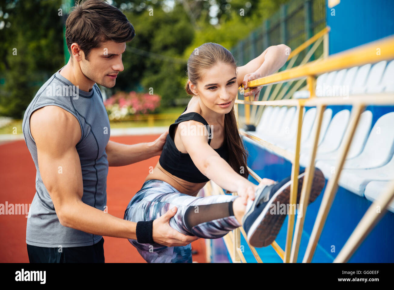 Süße junge Sportlerin arbeiten mit personal Trainer auf Stadion ...