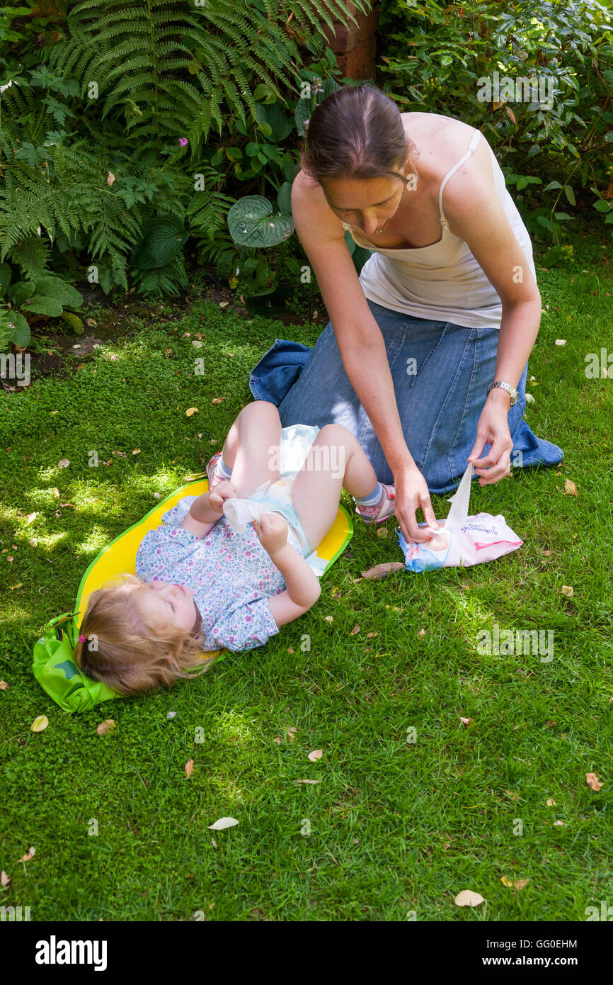 Mutter Mutter Eltern Betreuer Windelwechseln Windeln Baby Kleinkind ändern. Unter freiem Himmel Garten / außen / außen / Outdoor / outdoor Stockfoto