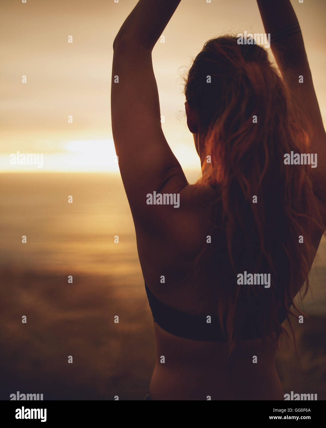 Silhouette Rückansicht der jungen Frau praktizieren Yoga bei Sonnenuntergang, Asana mit Händen über dem Kopf zu tun. Stockfoto