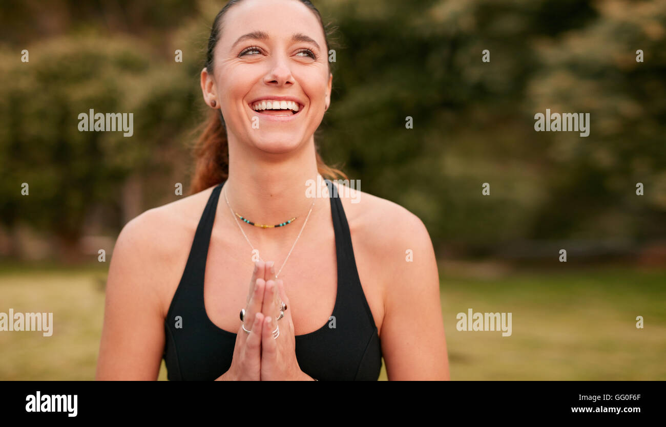 Porträt einer selbstbewussten, sportlichen Frau, die Yoga praktiziert, blickt weg und lächelt. Fitness-Frau trägt Sport-BH mit den Händen Jo Stockfoto