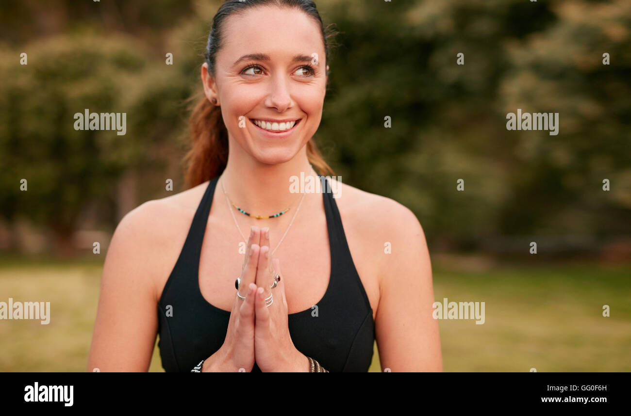 Porträt einer selbstbewussten jungen Frau, die Yoga macht, wegschaut und lächelt. Fitness-Frau trägt Sport-BH mit verbundenen Händen. Stockfoto