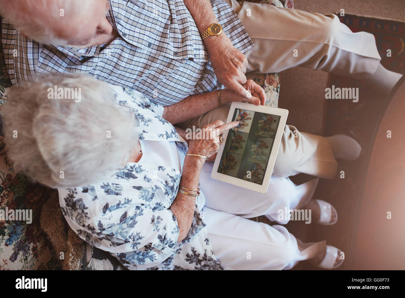 Draufsicht auf älteres Paar, sitzen, zusammen mit Blick auf Bilder auf digitale Tablet. Reifer Mann und Frau sitzt auf dem Sofa, auf der Suche ich Stockfoto