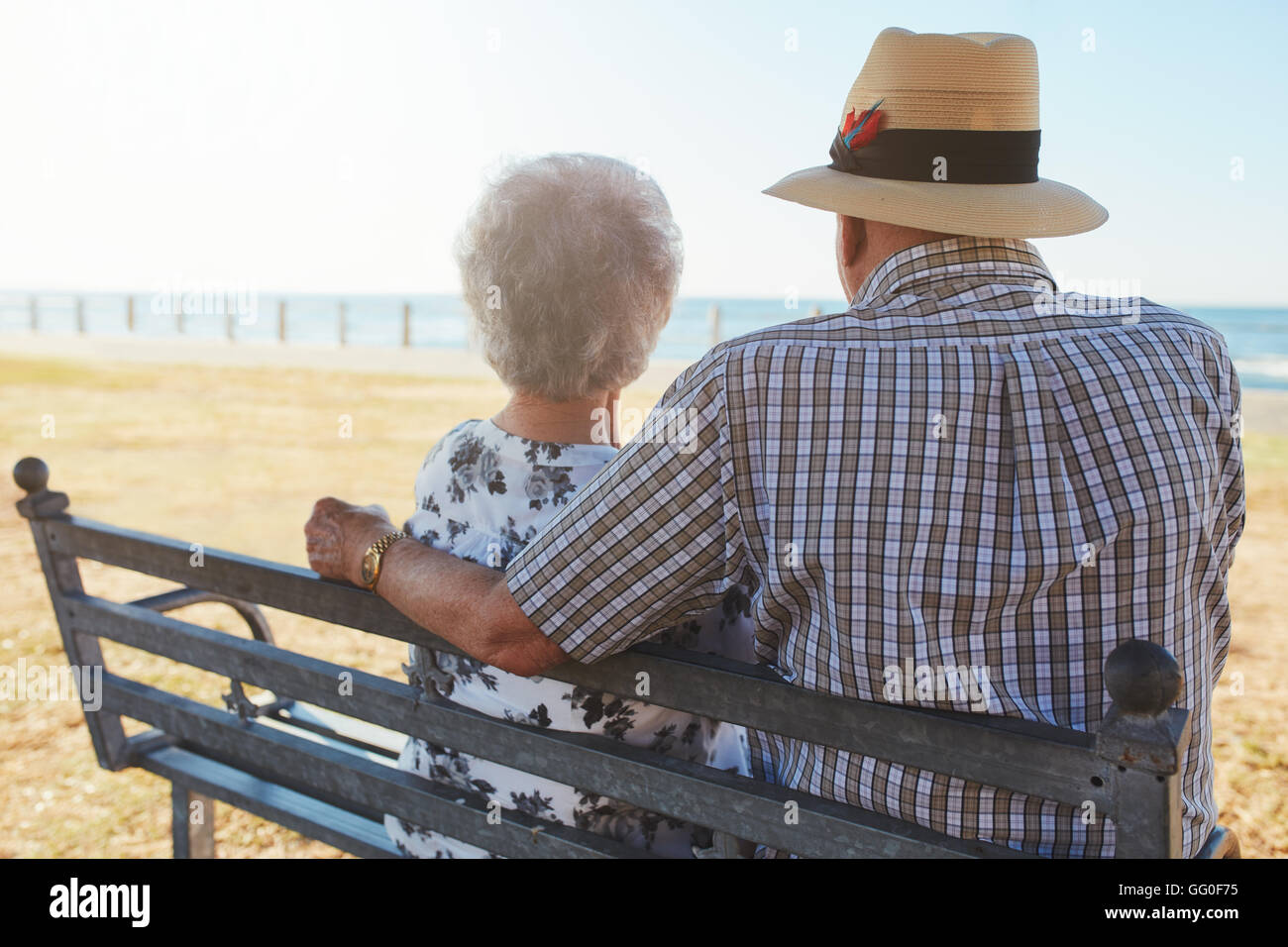 Ansicht von hinten Nahaufnahme Schuss älterer Mann und Frau sitzen auf einer Bank im Freien und Blick auf das Meer. Älteres Paar sitzt auf einem Stockfoto