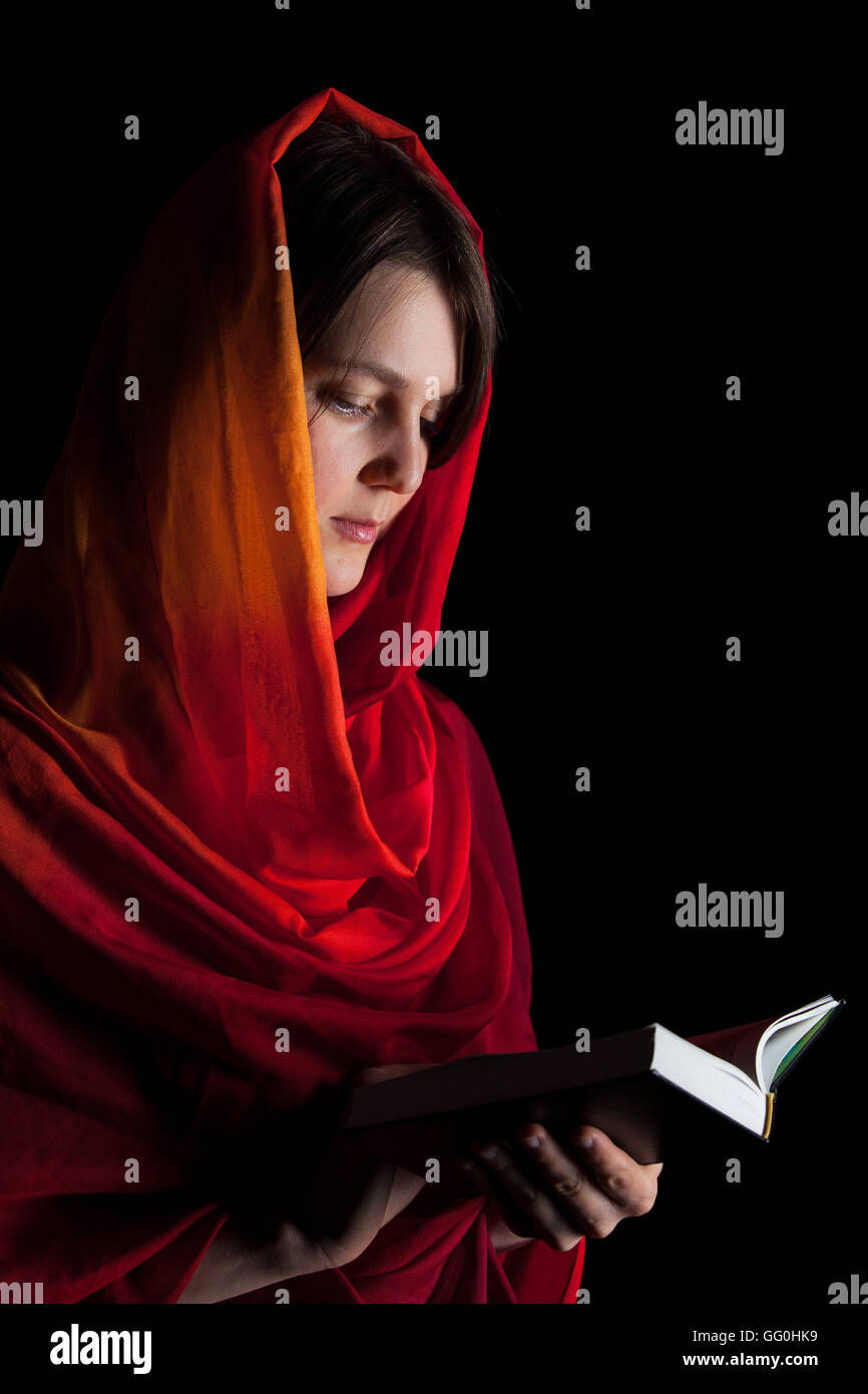 Frau liest eine Bibel in der Nacht. Auf schwarzem Hintergrund isoliert Stockfoto