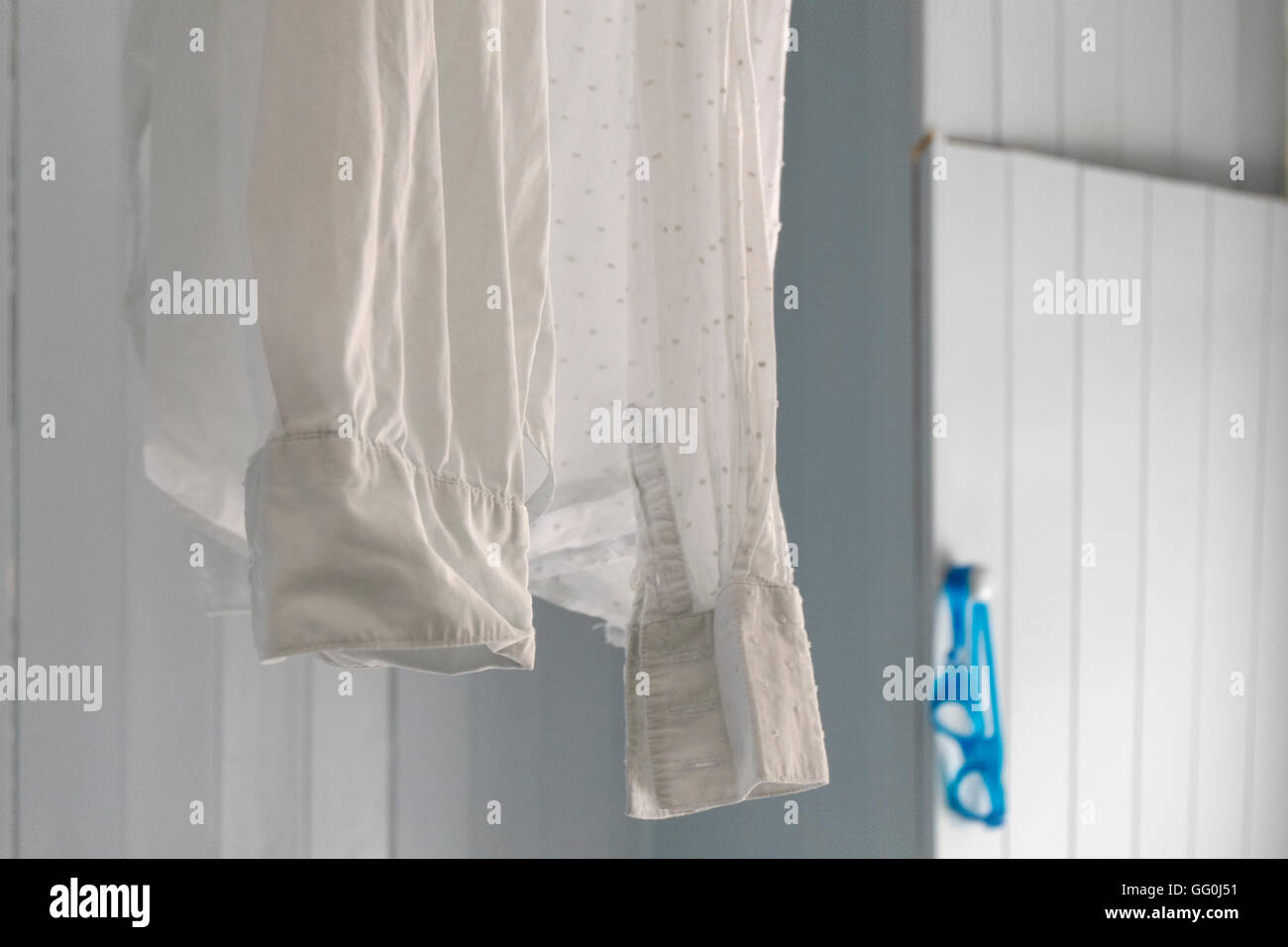 Weißes Hemd zum Trocknen auf eine Vorhangschiene Dusche im Badezimmer aufgehängt. Stockfoto
