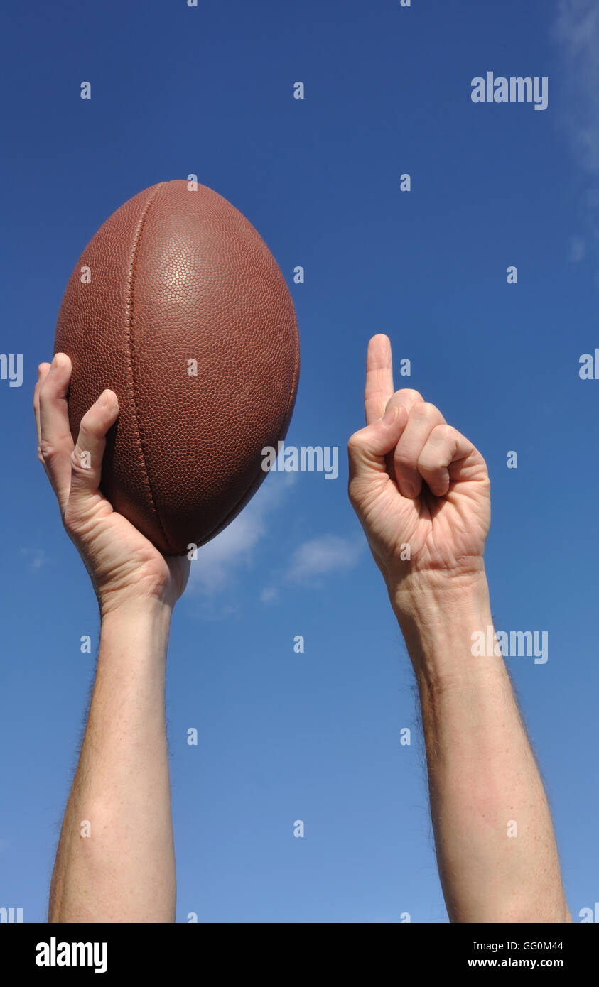 US-amerikanischer Footballspieler feiert einen Touchdown hält ein American Football und geben eine Zahl einen Zeichen Stockfoto