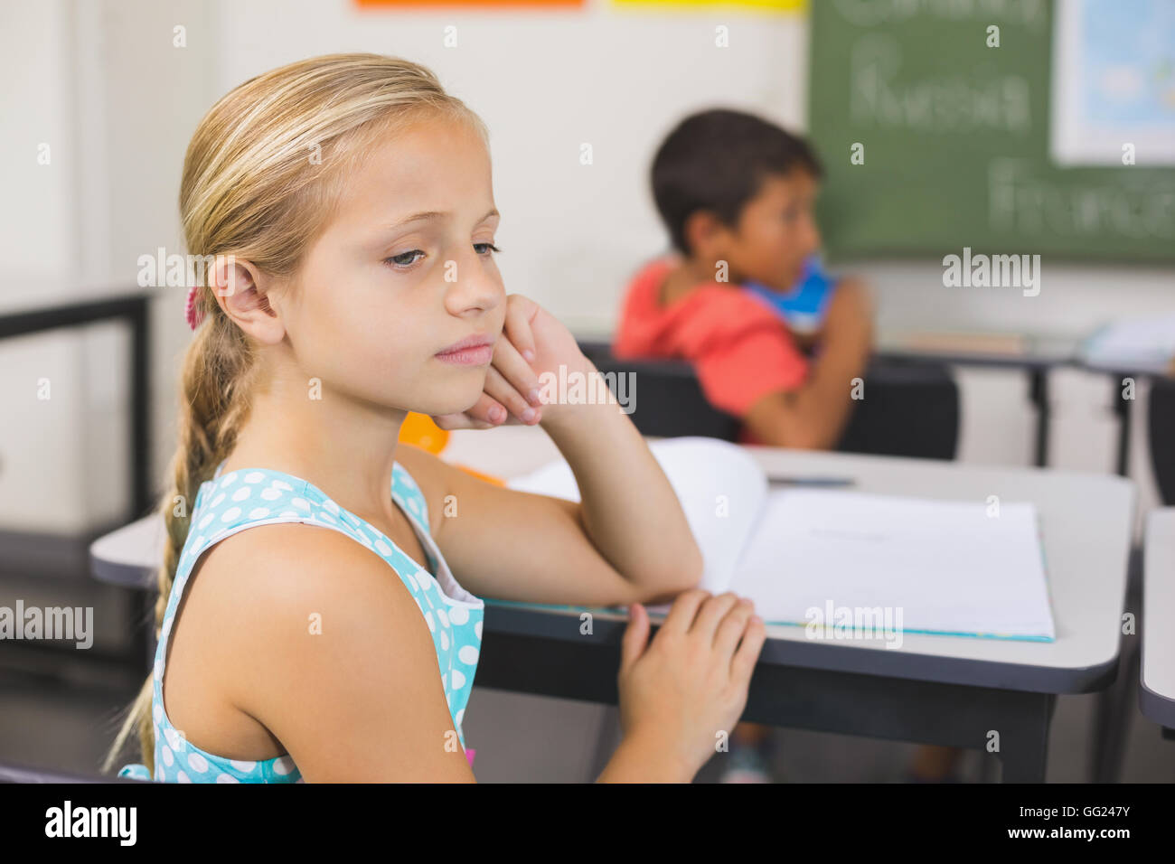 Nachdenklich Schulmädchen sitzen am Schreibtisch mit Hand auf Gesicht Stockfoto