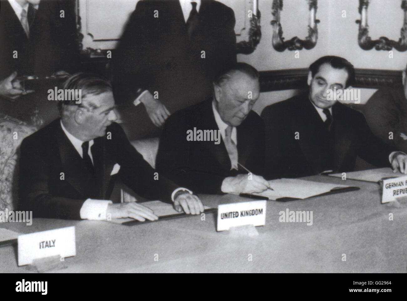 Adenauer, umgeben von Eden und Mendès-France, unterzeichnet das Abkommen über Aufrüstung und deutschen Souveränität. Oktober 1954 England - London National Archives - Washington Stockfoto