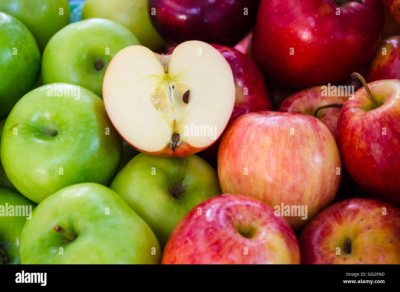 halben Apfel auf Gruppe von grünen und roten Äpfeln Stockfoto