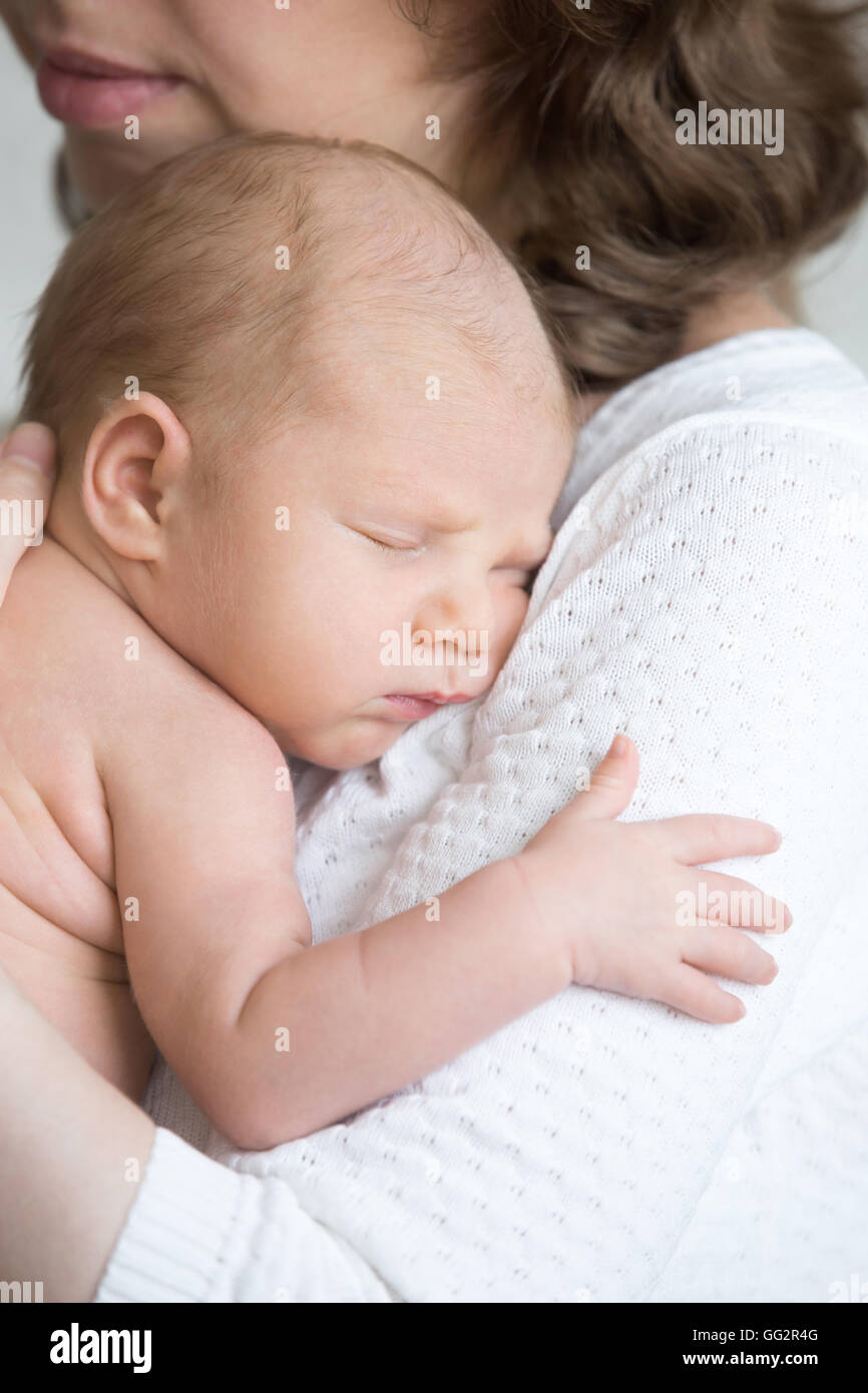 Porträt der jungen Mutter zärtlich umarmen schlafenden niedlichen neugeborenen Kindes. Lustige neugeborenes Baby Nickerchen im Mom Arme Stockfoto