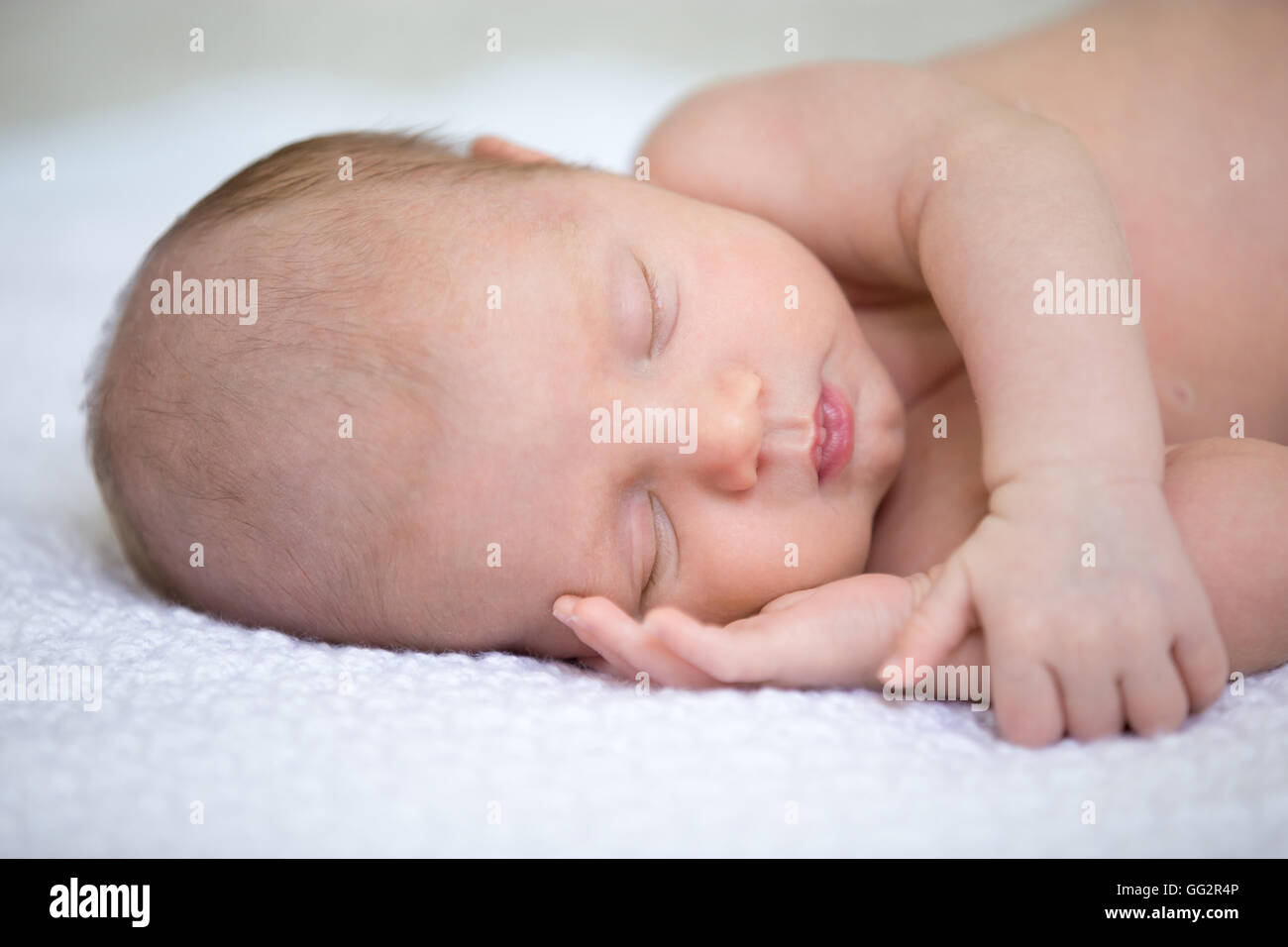Portrait von junge lustige Neugeborene Babe Nickerchen auf weiße gestrickte Decke mit Arm unter Wange. Süße kaukasische Neugeborene Stockfoto