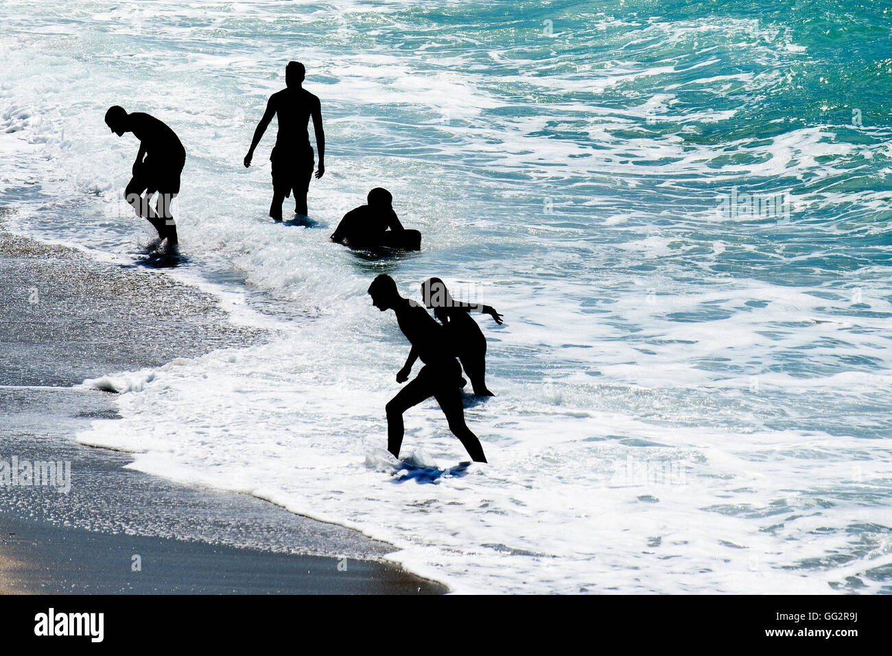 Leute, die in der Silhouette spielen im Meer in Newquay, Cormnwall gesehen. Stockfoto