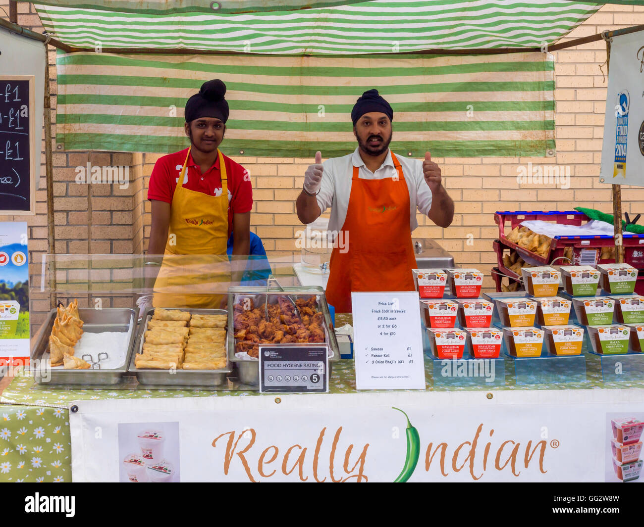 Sikh-Männer Marktfahrer am bei der jährlichen Saltburn Food Festival servieren gekocht "Wirklich indischen" Essen Daumen. Stockfoto